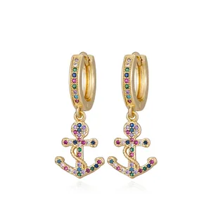 Close-up of golden anchor earrings with colorful cubic zirconia and maritime design
