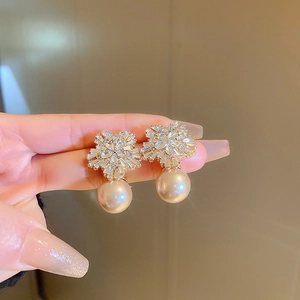 Macro shot of snowflake earrings with zircon stones and champagne gold pearls