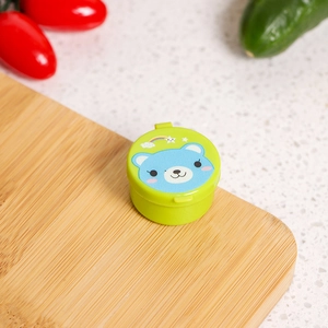 Close-up of portable mini sauce container with cute bear pattern on a wooden board