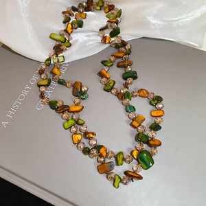 Detail of beaded necklace with green shell pieces and champagne crystal beads on silk