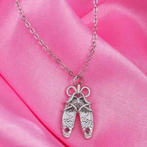 Detailed close-up of silver ballet shoe pendant with pink rhinestones on silk