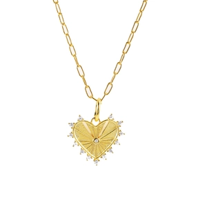 Close-up of golden heart pendant with radial texture and stones on a paperclip chain