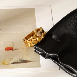 Detail of 18k gold heart ring with pavé diamonds hanging on a black leather bag