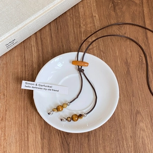 Détail d'un collier bohème avec perles en céramique et éléments en bois sur fond en bois
