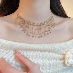 Close-up of elegant gold fringe necklace with small bead chains worn on female neck