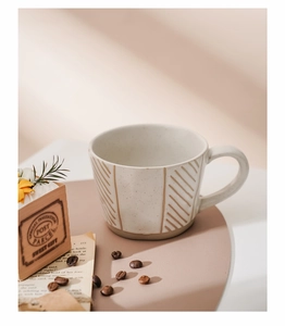 Detail of handmade stoneware mug with brown diagonal stripes and speckled glaze finish
