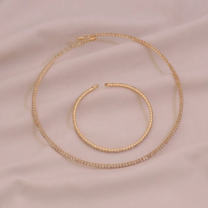 Detailed close-up of golden rhinestone collar necklace and bracelet on soft satin silk