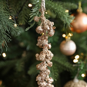 Sparkling champagne gold Christmas sequin tassel garland hanging on a festive pine tree