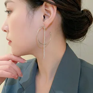 Orecchini a cerchio dorati minimalisti con nappe di zirconi indossati da modella