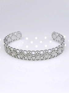 Detailed close-up of a silver stainless steel cuff bracelet with floral hollow design