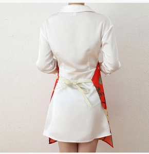 Detail of Christmas apron with red festive print tied over a white silk dress