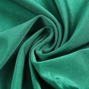Dettaglio macro del tessuto a maglia verde smeraldo con lucentezza setosa e pieghe