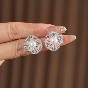 Close-up of silver hollow floral earrings with blue accents and round white pearls