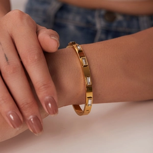 Gros plan d'un bracelet en acier inoxydable doré orné de zircons rectangulaires au poignet