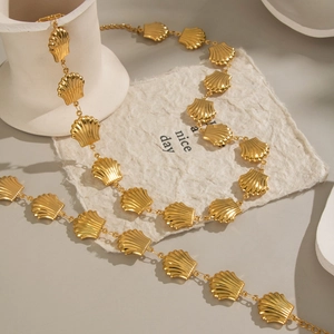Gold stainless steel shell-shaped link necklace on textured paper with artistic styling