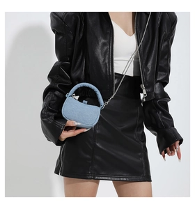Detail of light blue denim mini handbag with padded handle and silver chain strap