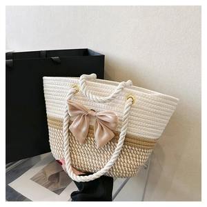 Close-up of woven cotton tote bag featuring beige ribbon bow and thick rope handles