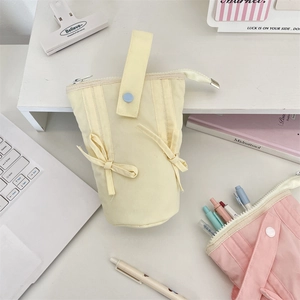Vertical canvas pencil case with cute bow and portable handle shown on a bright desk