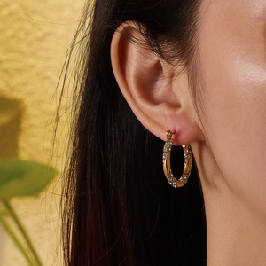 Macro shot of 18k gold plated C-shaped twisted earrings with sparkling inlaid diamonds