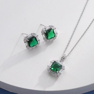 Detailed close-up of emerald square halo necklace and earrings jewelry set on a white stand