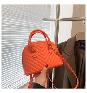 Close-up of vibrant orange quilted shell bag with gold hardware and shoulder strap