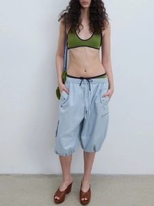 Detail of light blue cargo capris featuring drawstring waist and functional zipper pockets