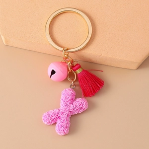 Detail of pink resin letter X keychain featuring rose floral texture and soft tassel