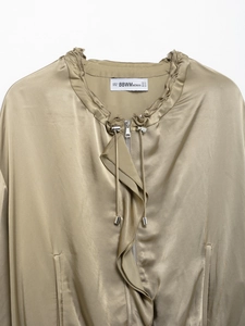 Detailed close-up of olive green satin jacket collar with drawstring and brand label