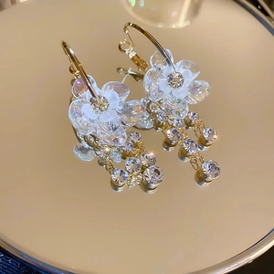 Orecchini a fiori con strass scintillanti e nappe di cristallo su superficie a specchio