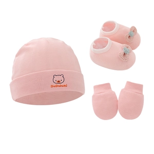 Close-up of pink cotton knit infant set including hat, booties and gloves with bear embroidery