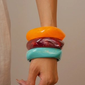 Close-up of geometric resin bangles in orange, burgundy and teal marble finish