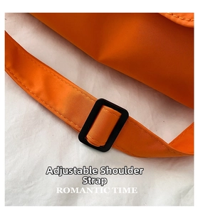 Detail of adjustable nylon shoulder strap and matte buckle on orange crossbody bag