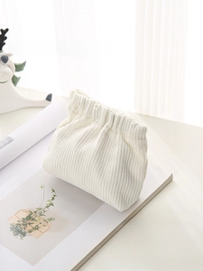 Detailed texture of off-white corduroy mini makeup bag on clean minimalist background