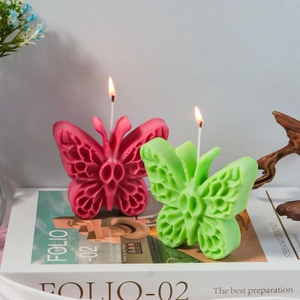 Dettaglio di candele a forma di farfalla rosa e verde con trame d'ali intricate