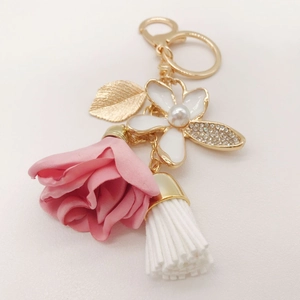 Detail of pink fabric rose and pearl rhinestone flower keychain with a gold leaf and tassel