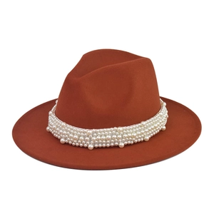 Detalle de perlas incrustadas en sombrero fedora de lana rojo óxido con ala ancha