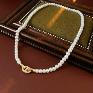 Macro detail of French vintage pearl necklace with gold H-link zircon clasp