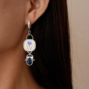 Détail d'une boucle d'oreille tulipe en céramique avec goutte bleue sur mannequin