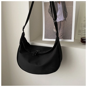 Close-up of black nylon crescent crossbody bag with adjustable strap and zip detail