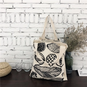 Detailed texture of leaf print canvas tote bag on a rustic wooden surface backdrop