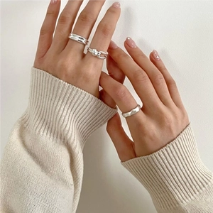 Detailed view of handmade textured 925 silver rings worn with a beige knitted sweater