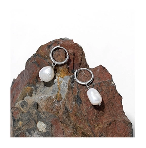Macro view of baroque pearls on silver hoops showcased against natural reddish brown rock