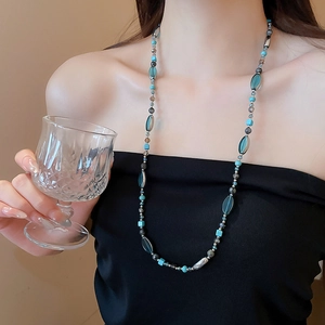 Détail du collier de perles avec cubes géométriques bleus et pierres sur modèle