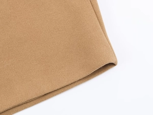 Close-up of camel-colored wool blend fabric texture showing thick material and neat edges
