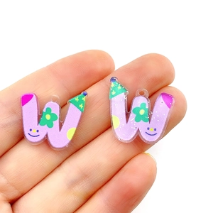 Close-up of purple acrylic letter W pendants with colorful flower and smiley face patterns