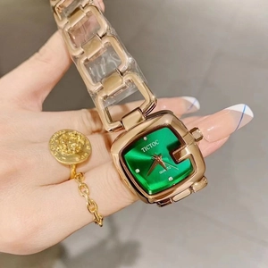 Detail shot of a women's vintage square green watch with a gold chain bracelet on wrist