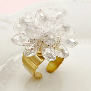 Macro detail of gold stainless steel ring with 3D crystal flower design on white relief