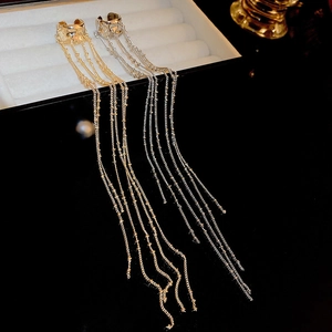 Detail of gold and silver chain tassel ear cuffs on a jewelry box edge