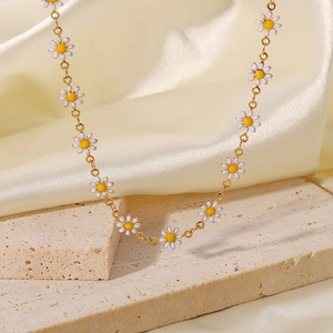 Vista detallada de dijes de margaritas en el collar de acero de titanio chapado en oro 18K