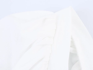 Detailed macro view of white pleated fabric texture and stitched hem on the puff sleeve top